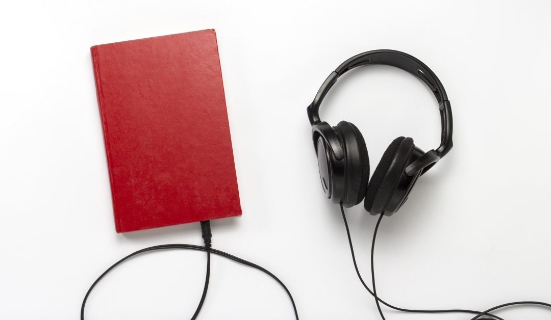 Kuvituskuva jossa valkoisella taustalla punainen kirja johon menee mustien kuulokkeiden johto